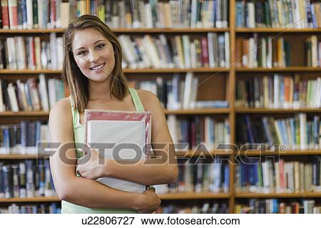Student carrying books in library View Large Photo Image Stock Photo - Student carrying books in library. Fotosearch