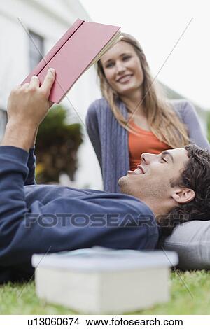 Picture - Student reading on grass on campus. Fotosearch