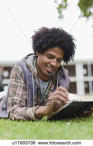 Stock Photo - Student reading on grass on campus. Fotosearch