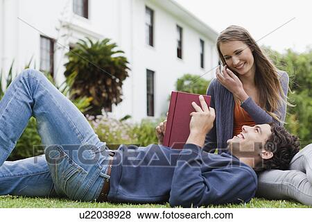 Stock Photo - Student reading on grass on campus. Fotosearch