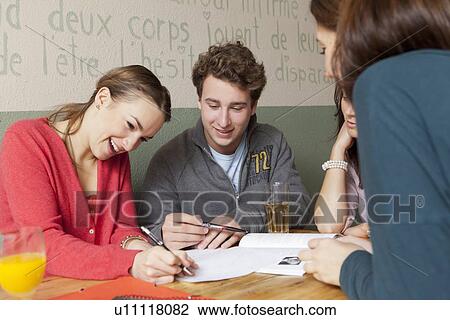 Stock Image - Students studying together in cafe. Fotosearch