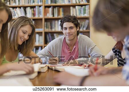 Stock Image - Students studying together in library. Fotosearch