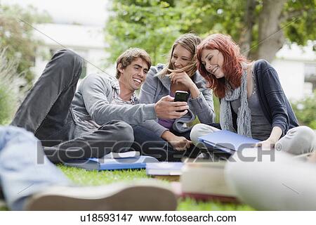 Stock Photo - Students using cell phone on grass. Fotosearch