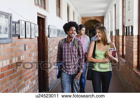 Stock Image - Students walking together in hallway. Fotosearch