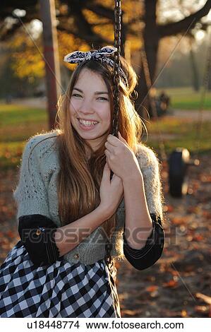 Teenage girl sitting on park swing View Large Photo Image Picture - Teenage girl sitting on park swing. Fotosearch