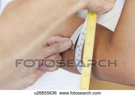 Trainer measuring girls arm in gym View Large Photo Image Stock Photograph - Trainer measuring girls arm in gym. Fotosearch