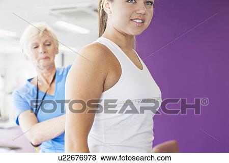 Stock Photo - Trainer measuring girls bust in gym. Fotosearch