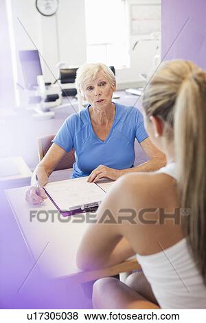 Stock Photo - Trainer speaking with woman in gym. Fotosearch
