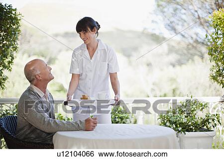 Waitress serving older man coffee View Large Photo Image Stock Photograph - Waitress serving older man coffee. Fotosearch