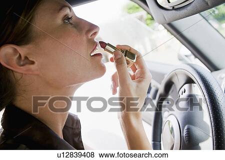 Woman applying lipstick in car mirror View Large Photo Image Stock Photo - Woman applying lipstick in car mirror. Fotosearch