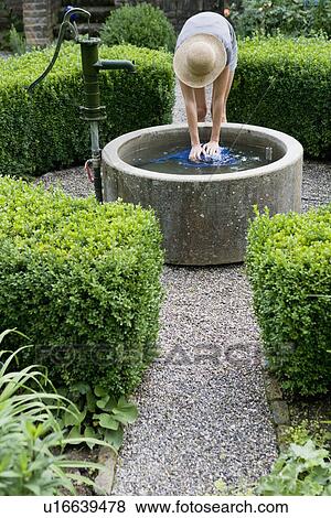 Woman filling watering can in pond View Large Photo Image Stock Photo - Woman filling watering can in pond. Fotosearch