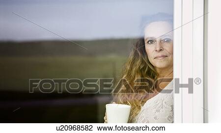 Woman having cup of coffee at window View Large Photo Image Stock Image - Woman having cup of coffee at window. Fotosearch
