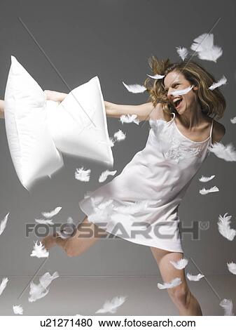 Stock Image - Woman having pillow fight. Fotosearch