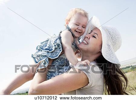 Stock Image - Woman holding daughter outdoors. Fotosearch