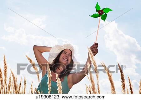 Stock Image - Woman holding pinwheel in wheatfield. Fotosearch