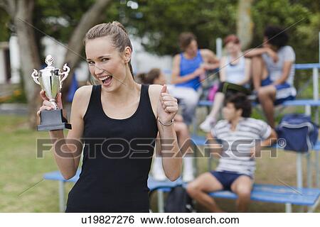 Stock Photograph - Woman holding trophy in park. Fotosearch