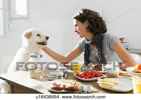 Picture - Woman petting dog at table. Fotosearch