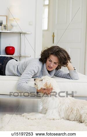 Stock Image - Woman petting dog in living room. Fotosearch