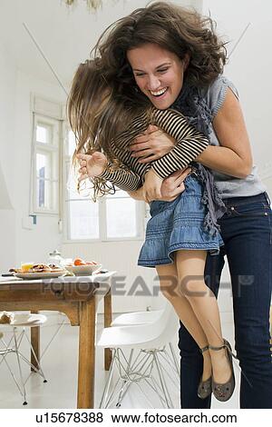 Stock Photo - Woman playing with daughter in kitchen. Fotosearch