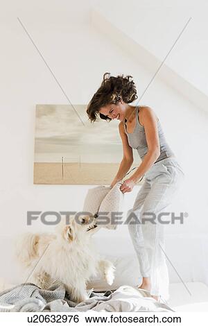 Stock Photograph - Woman playing with dog in bed. Fotosearch