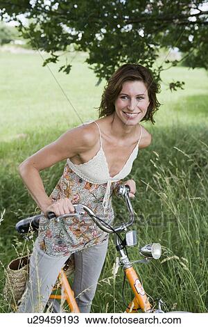 Woman pushing bicycle in tall grass View Large Photo Image Stock Image - Woman pushing bicycle in tall grass. Fotosearch