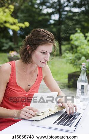Woman reading and using laptop outdoors View Large Photo Image Stock Photo - Woman reading and using laptop outdoors. Fotosearch