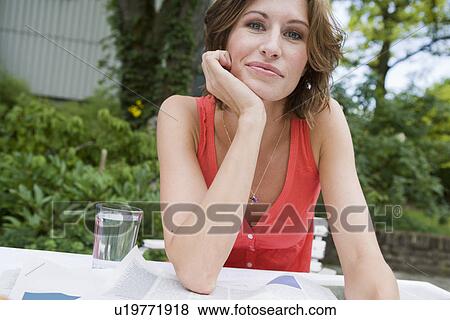 Stock Photo - Woman reading newspaper in backyard. Fotosearch