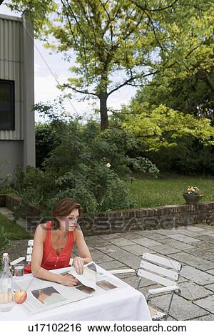 Stock Photograph - Woman reading newspaper in backyard. Fotosearch