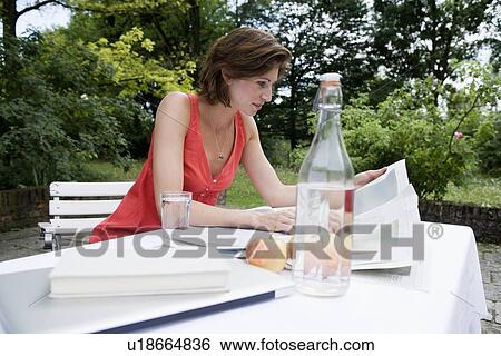 Stock Photograph - Woman reading newspaper in backyard. Fotosearch