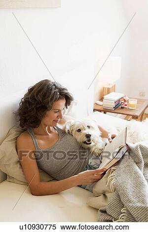 Woman reading with dog in bed View Large Photo Image Stock Photography - Woman reading with dog in bed. Fotosearch
