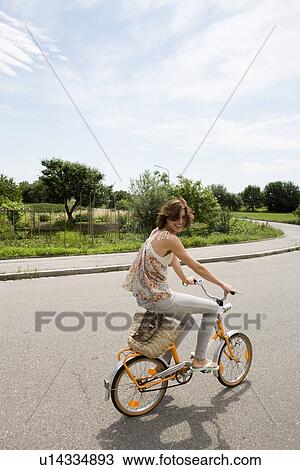 Woman riding bicycle on rural road View Large Photo Image Stock Image - Woman riding bicycle on rural road. Fotosearch
