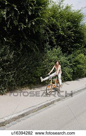 Woman riding bicycle on rural road View Large Photo Image Stock Image - Woman riding bicycle on rural road. Fotosearch