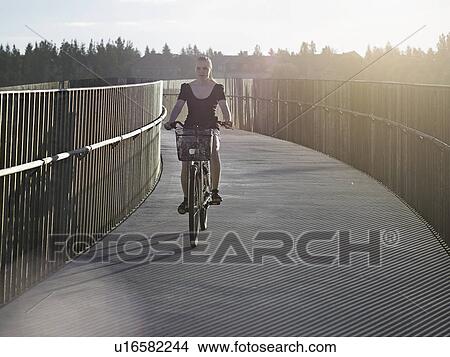 Woman riding bicycle on skybridge View Large Photo Image Picture - Woman riding bicycle on skybridge. Fotosearch