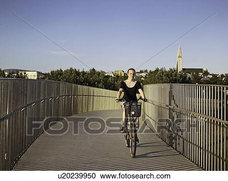 Stock Image - Woman riding bicycle on skybridge. Fotosearch
