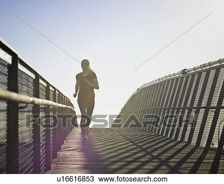 Stock Image - Woman running on skybridge. Fotosearch