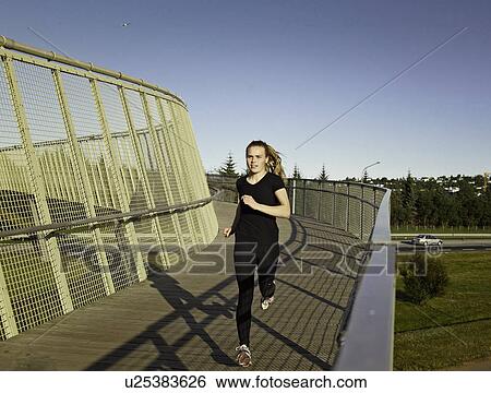Stock Photograph - Woman running on skybridge. Fotosearch
