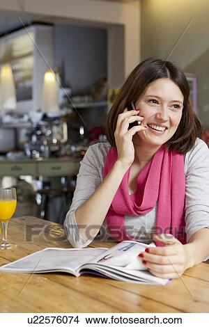 Woman talking on cell phone in cafe View Large Photo Image Picture - Woman talking on cell phone in cafe. Fotosearch