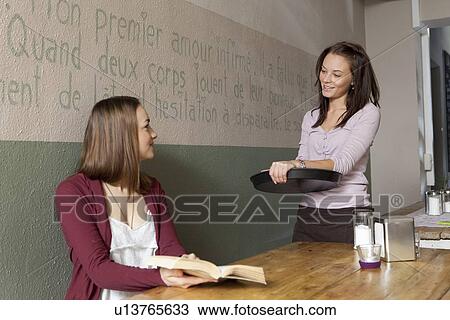 Stock Image - Woman talking to waitress in cafe. Fotosearch
