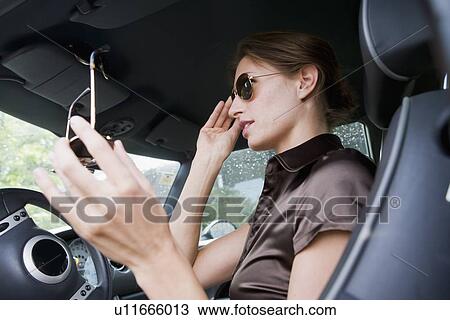 Stock Image - Woman trying on sunglasses in car. Fotosearch