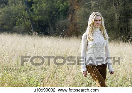 Stock Image - Woman walking in wheatfield. Fotosearch