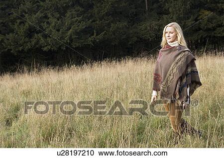 Stock Image - Woman walking in wheatfield. Fotosearch