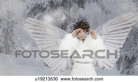 Stock Image - Woman wearing white wings in snow. Fotosearch