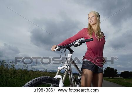 Woman wheeling bicycle on rural road View Large Photo Image Stock Photo - Woman wheeling bicycle on rural road. Fotosearch