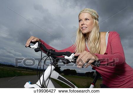 Woman wheeling bicycle on rural road View Large Photo Image Stock Photo - Woman wheeling bicycle on rural road. Fotosearch