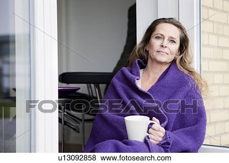 Stock Photo - Woman with coffee in blanket outdoors. Fotosearch