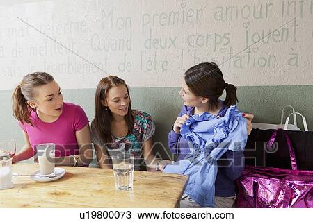 Stock Image - Women admiring clothes in cafe. Fotosearch