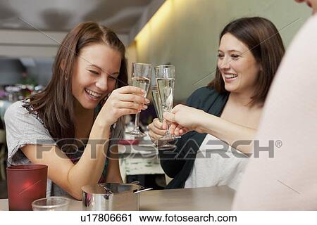 Stock Image - Women toasting with champagne in cafe. Fotosearch