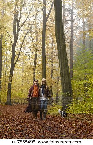 Stock Photography - Women walking dog in forest. Fotosearch