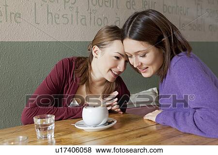Women whispering to each other in cafe View Large Photo Image Stock Photo - Women whispering to each other in cafe. Fotosearch