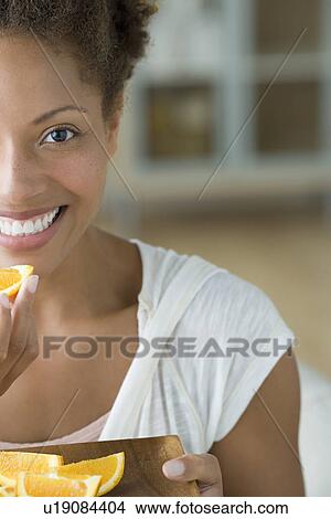 Picture - Attractive woman eating orange. Fotosearch